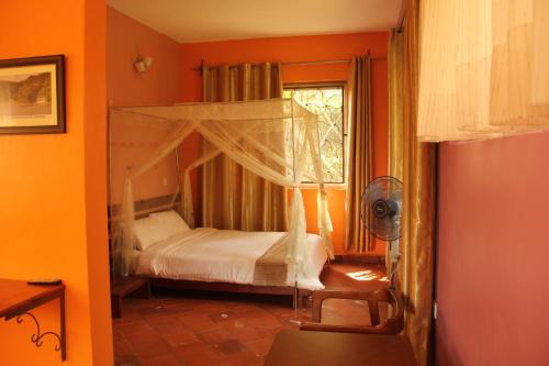 ein Schlafzimmer mit einem Himmelbett und einem Fenster in der Unterkunft Saltek Forest Cottages in Masindi