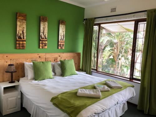 a bedroom with a large bed with green walls at Seaside Lodge B&B in Ballito