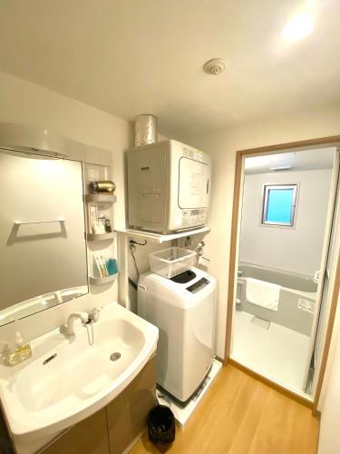 a small bathroom with a sink and a microwave at M´s Stay Okinawa in Chatan