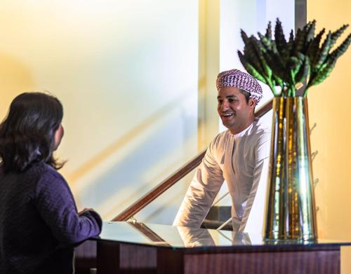 a man sitting at a table talking to a woman at Sahab Resort and Spa, Jabal Al Akhdar in Al ‘Aqar