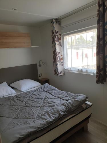 a bedroom with a bed and a window with curtains at Camping les dunes de contis in Saint-Julien-en-Born