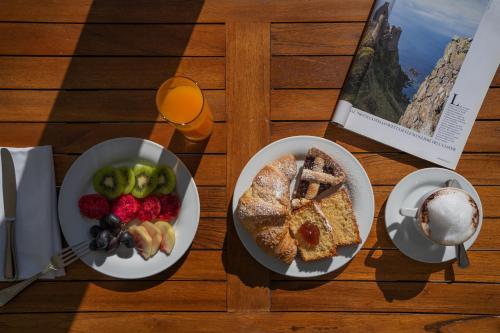 Maison Montechiaro في فيكو إيكوينس: طاولة خشبية مع طبقين من الطعام والفواكه