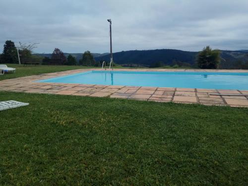 a large swimming pool in a grassy field at Chácara Áquila in São Roque