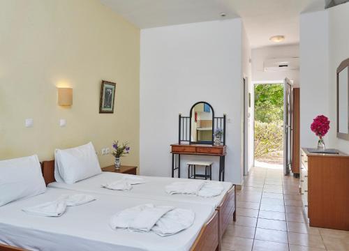 a bedroom with a bed with white sheets and a table at Lindos Athena in Lindos