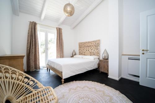 a bedroom with a bed and a chair and a window at Villa le Fontanelle in Gasperina