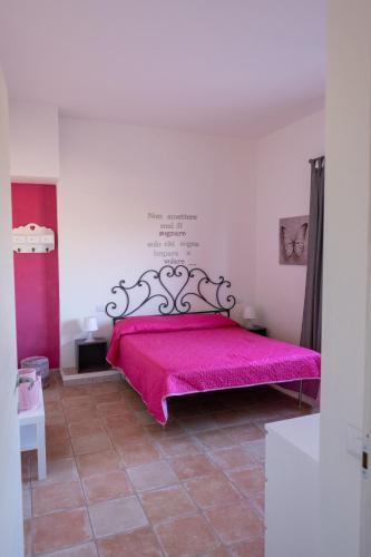 a bedroom with a pink bed in a room at Le casette di Frà al Bondì in Santa Severa
