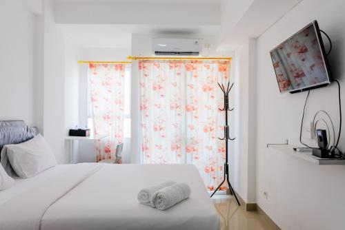 a bedroom with a white bed and a window at Comfortable and Fully Furnished Studio at Poris 88 Apartment By Travelio in Tangerang