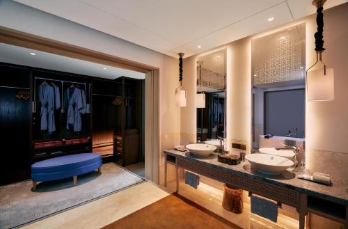 a bathroom with two sinks and two mirrors at Capella Tufu Bay, Hainan in Sanya