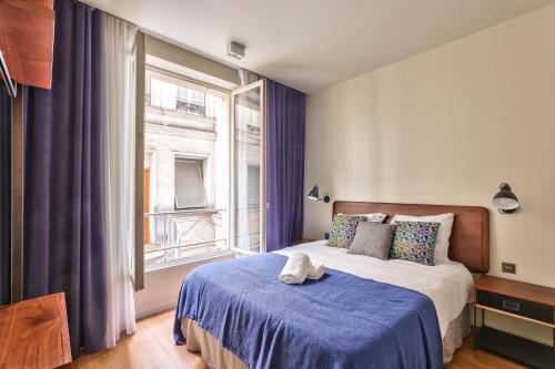une chambre avec un lit avec une couverture bleue et une fenêtre dans l'établissement 79 - Urban Love Le Marais, à Paris