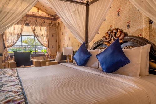 a bedroom with a large bed with blue pillows at Rawai Luxury Tents Pushkar in Pushkar