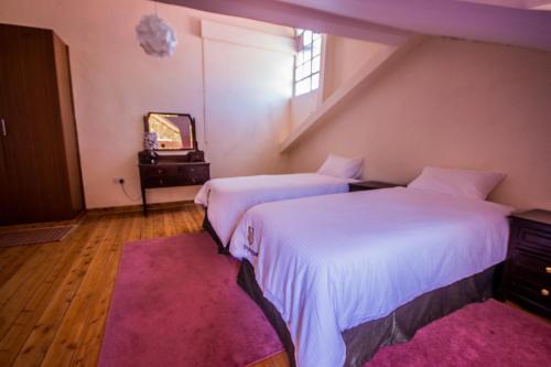 duas camas num quarto com um tapete rosa em Riverfront Gardens em Mjini