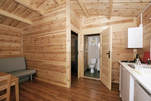 uma casa de banho com paredes de madeira e um WC num quarto em Holiday Resort & Camping InterCamp'84 em Leba