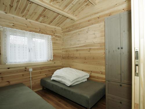 Blockhütte mit einem Bett und einem Fenster in der Unterkunft Holiday Resort & Camping InterCamp'84 in Łeba