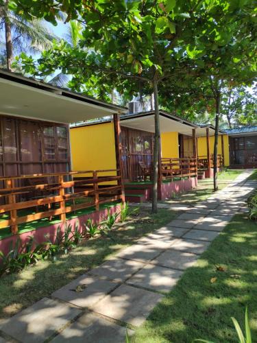 a row of buildings with wooden benches and trees at Sea Front Beach Huts in Patnem