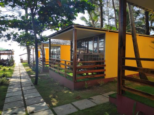 a yellow house with a fence in front of it at Sea Front Beach Huts in Patnem