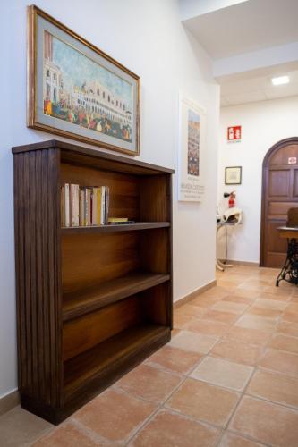 a book shelf in a hallway with a painting on the wall at Le casette di Frà al Bondì in Santa Severa