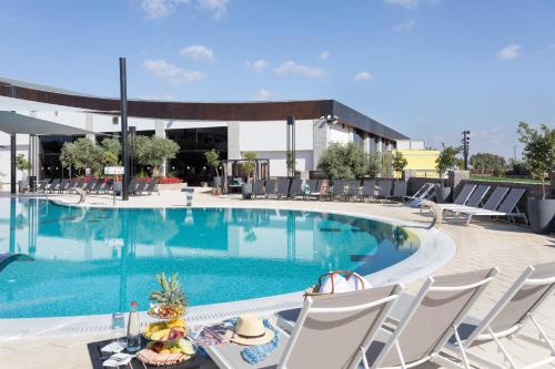 a pool with chairs and a table with food on it at Dream Island Spa & Health Resort in Sede Yo‘av