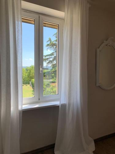 a window with a white curtain in a room at THE BERGHOUSE - LA CASA SUL CLIVO with JACUZZI in Bergamasco