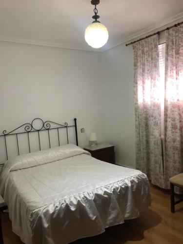 a bedroom with a bed and a lamp and curtains at Pensión Ruiz in Linares