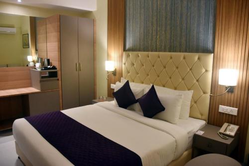 a hotel room with a large bed with blue and white pillows at Abbott Hotel in Navi Mumbai