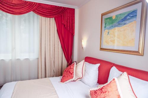 a bedroom with a bed with a red headboard and a window at Hotel Pushkin in Uralsk