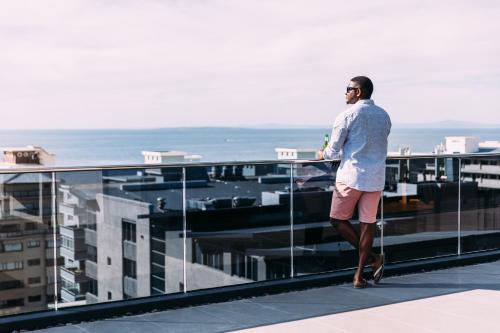 a man standing on the balcony of a building at Latitude Aparthotel by Totalstay in Cape Town
