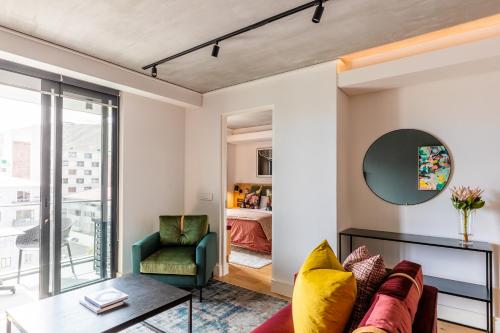 a living room with a couch and a chair and a bedroom at Latitude Aparthotel by Totalstay in Cape Town