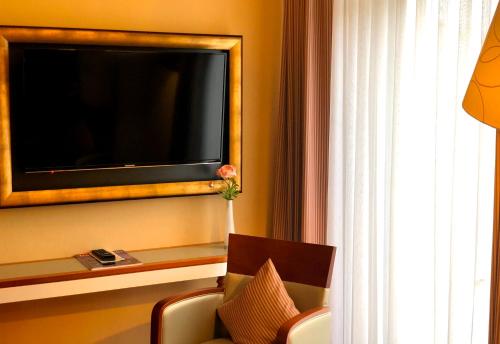 a hotel room with a tv on a wall with a chair at Hotel Kleiner Riesen in Koblenz