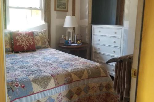 a bedroom with a bed and a dresser and a window at Old School House in Hallowell