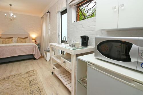 eine kleine Küche mit einer Mikrowelle und einem Bett in der Unterkunft Petite Apartment in Bellville