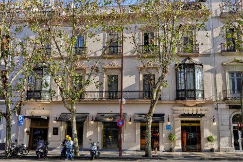 un edificio blanco con árboles delante de él en Hotel Lobby en Sevilla