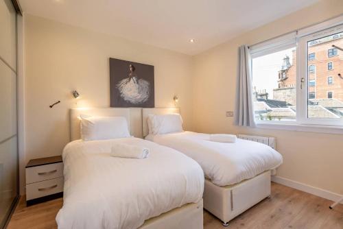 two beds in a room with a window at Pilmour Place - 30 Seconds to the Old Course! in St Andrews