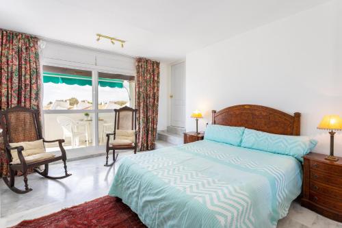 1 dormitorio con cama, sillas y ventana en Lunamar 82 Apartment by GHR Rentals, en Marbella