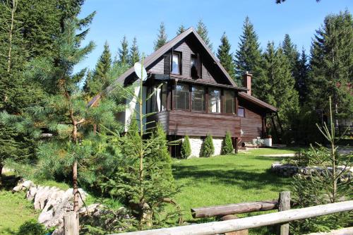 a wooden house in the woods with a fence at Planinska kuća MAK in Jahorina