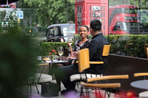 a man and a woman sitting at a table with wine glasses at The Athenaeum Hotel & Residences in London