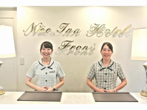 two women standing in front of a table with their laptops at Nice Inn Hotel Ichikawa Tokyo Bay in Urayasu