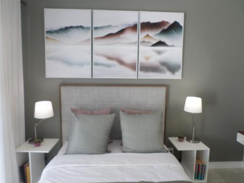 ein Schlafzimmer mit einem Bett mit vier Gemälden an der Wand in der Unterkunft The Blyde Crystal Lagoon Cologne3 in Greenview