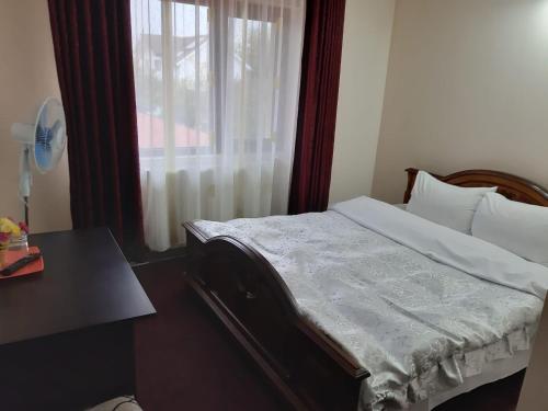 a bedroom with a bed with a window and a table at Pensiunea Hanami in Bacău