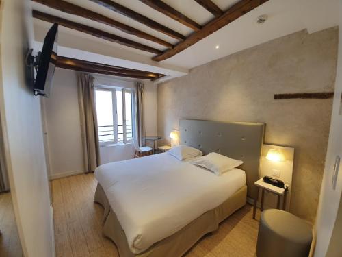a hotel room with a large bed and a large window at Hôtel De La Herse d'Or in Paris