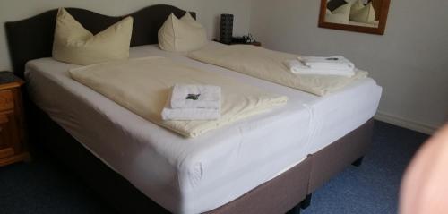 a bedroom with two beds with white sheets and towels at Hotel Holsteinische Schweiz am Dieksee in Malente