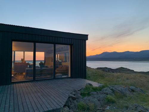 a house with a deck with a view of the ocean at Hvammsvík Nature Resort in Kjósahreppur