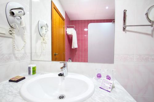 a white bathroom with a sink and a mirror at Hotel Servigroup La Zenia in Playas de Orihuela
