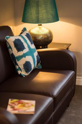 a brown leather couch with a pillow and a lamp at Riber Cottage - Darwin Lake Holiday Village in Matlock