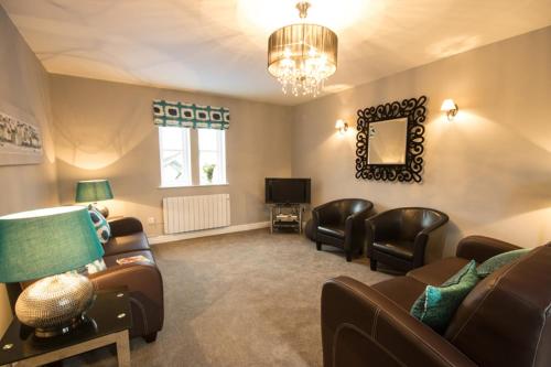 a living room with leather furniture and a television at Riber Cottage - Darwin Lake Holiday Village in Matlock