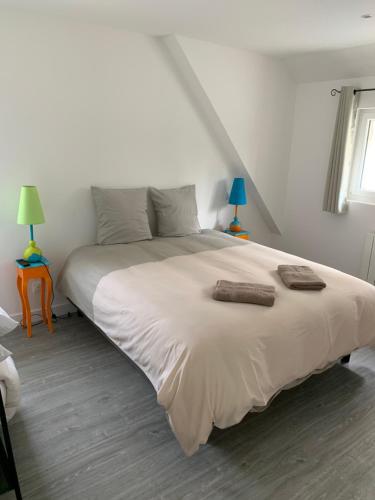 a bedroom with a large white bed with two lamps at gîte du moulin du pré in Bavent