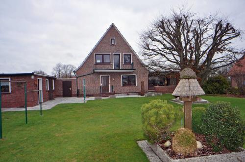 una casa con un patio de césped con una estatua delante de ella en Ferienwohnung An der Wieke, 65295, en Moormerland
