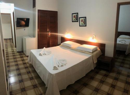 a bedroom with a large white bed in a room at Thanharu Praia Hotel in Anchieta