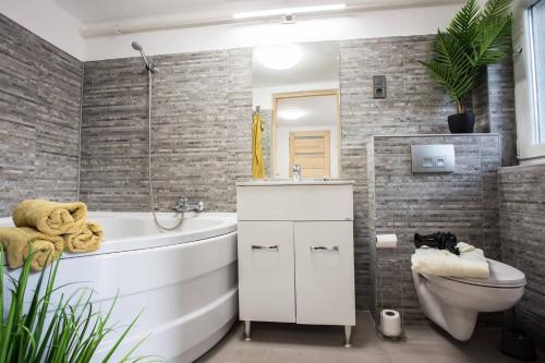 ein Badezimmer mit einer weißen Badewanne und einem WC in der Unterkunft Csigaház Apartman in Pécs