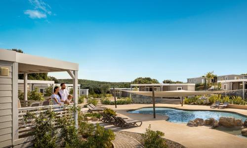 two people standing on the balcony of a house at Maistra Camping Veštar Mobile homes in Rovinj