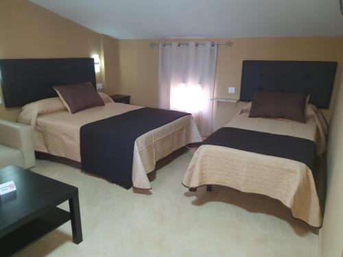 a hotel room with two beds and a table at Hostal Málaga in Arcos de la Frontera